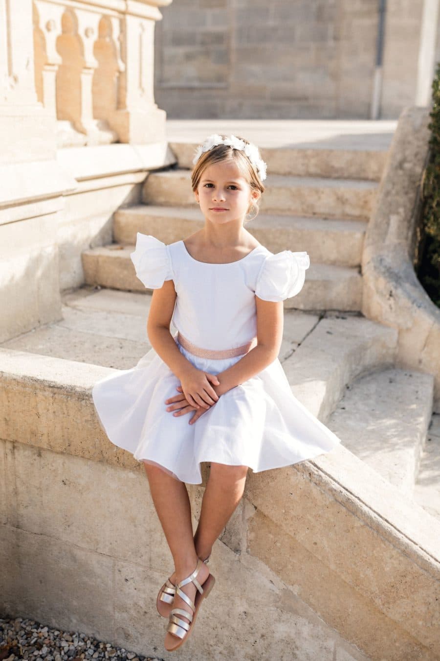 Petite fille assise sur les marches du château en tenue de cérémonie