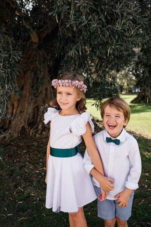 Petit garçon et petite fille d'honneur en tenue blanche et accessoires verts
